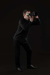 Professional photographer taking picture on black background