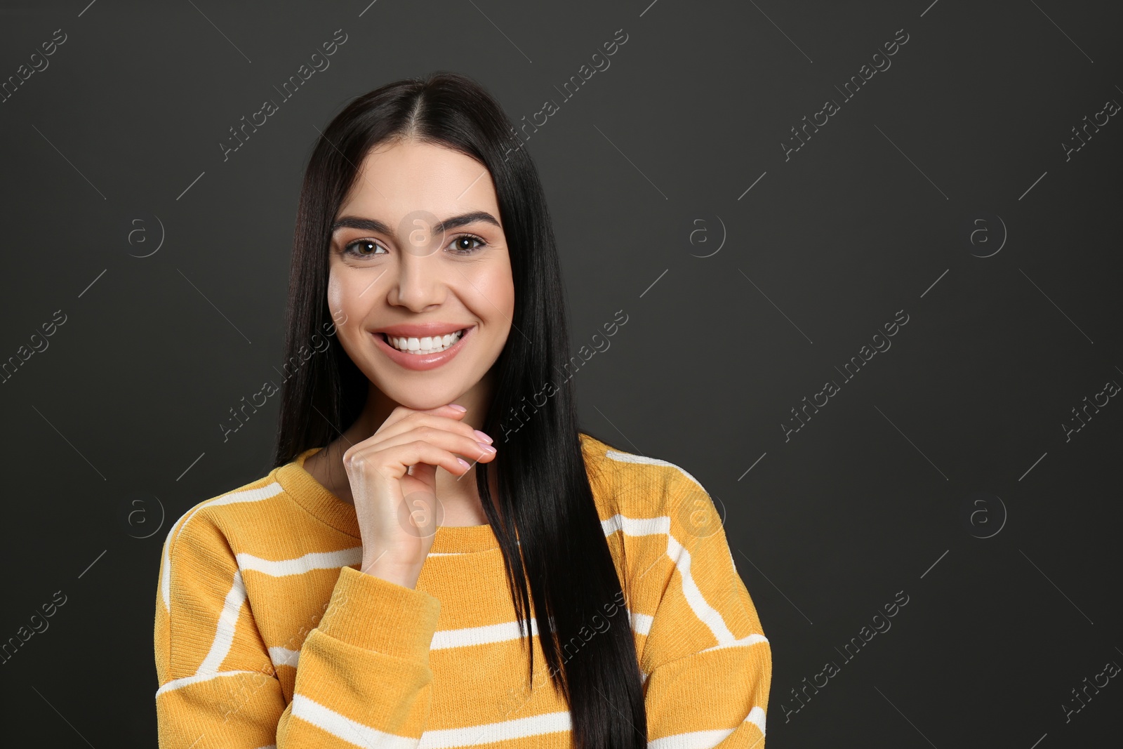 Photo of Portrait of happy young woman with beautiful black hair and charming smile on dark background, space for text