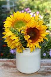 Bouquet of beautiful sunflowers in tin on wooden table outdoors