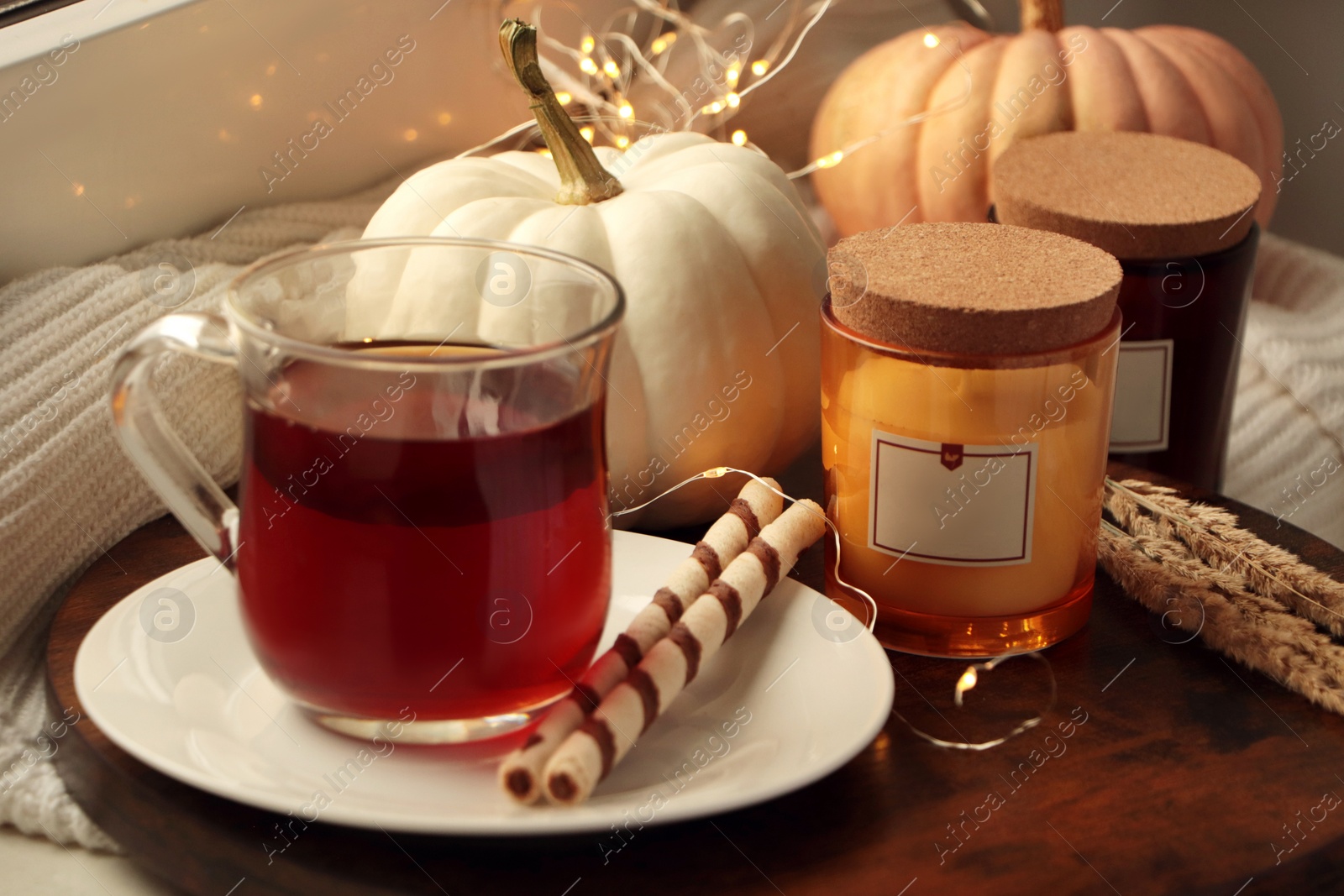 Photo of Cup of hot drink, cookies, candles and pumpkins on window sill indoors