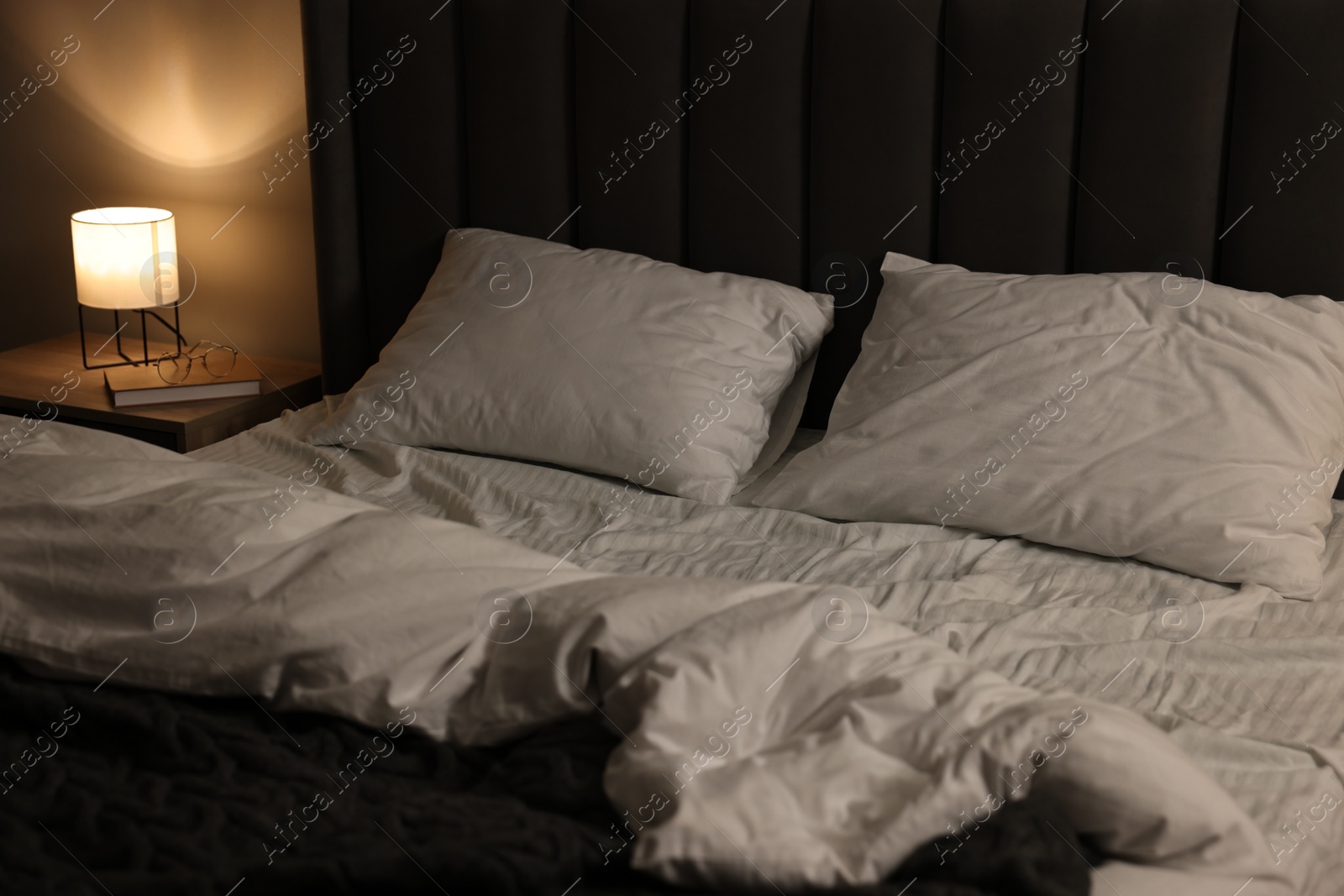 Photo of Soft bed and bedside table with nightlight indoors