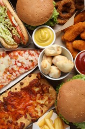 Photo of French fries, burgers and other fast food on wooden table, flat lay