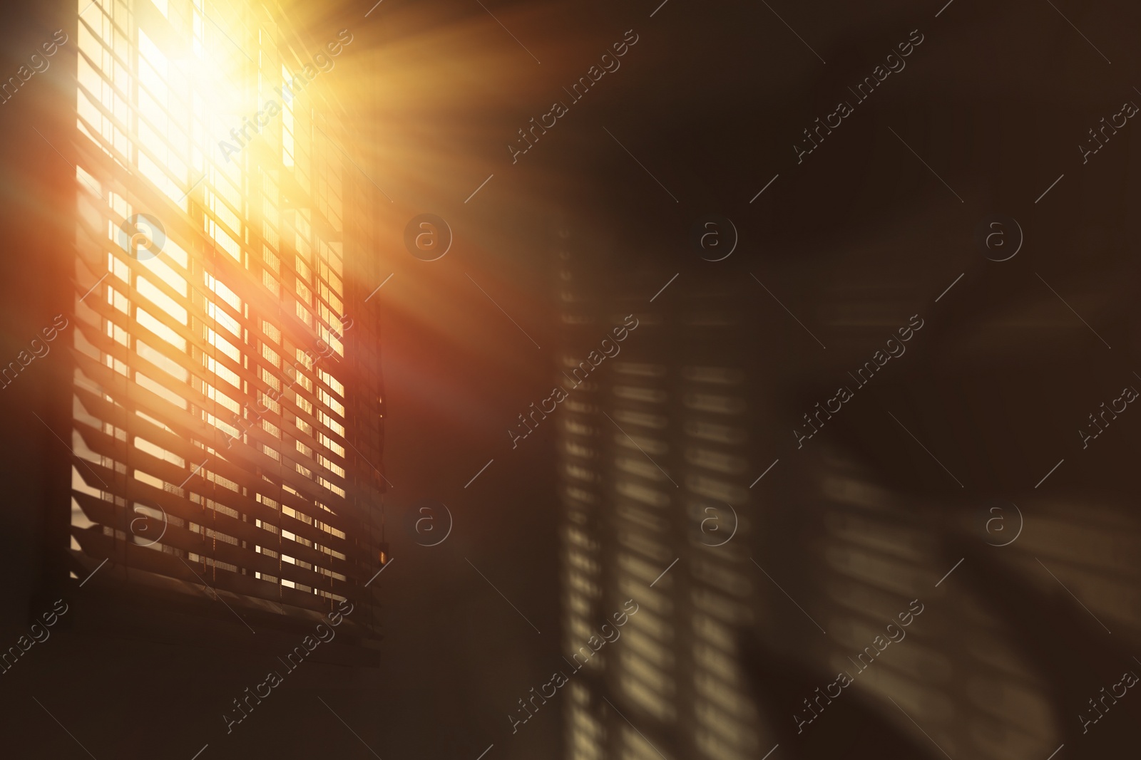 Image of Sun shining through window blinds in room