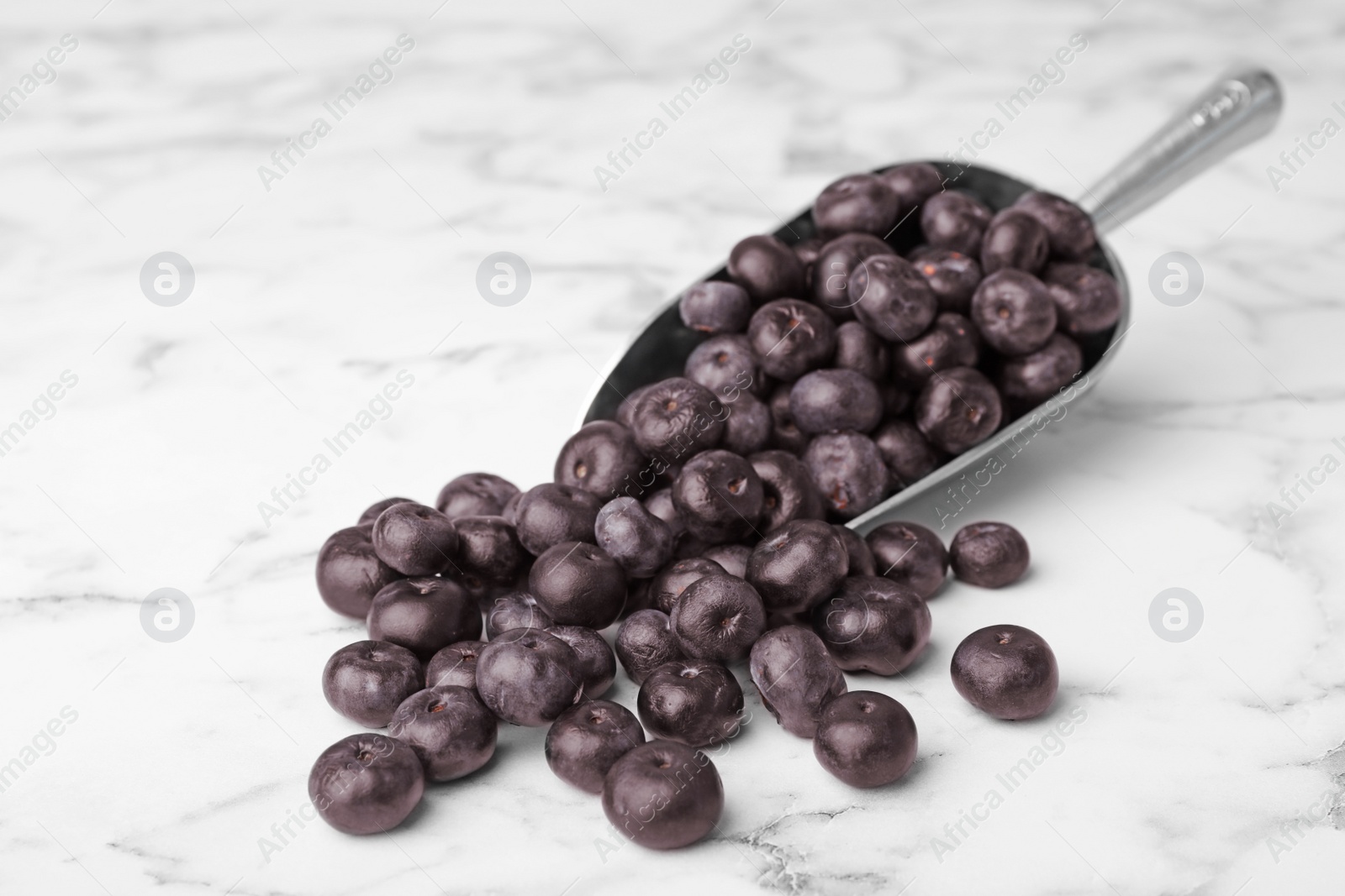 Photo of Metal scoop of fresh acai berries on marble table, space for text