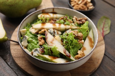 Photo of Delicious pear salad with sauce in bowl on wooden table, closeup