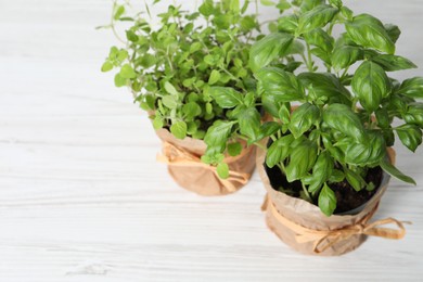 Photo of Different aromatic potted herbs on white wooden table, above view. Space for text