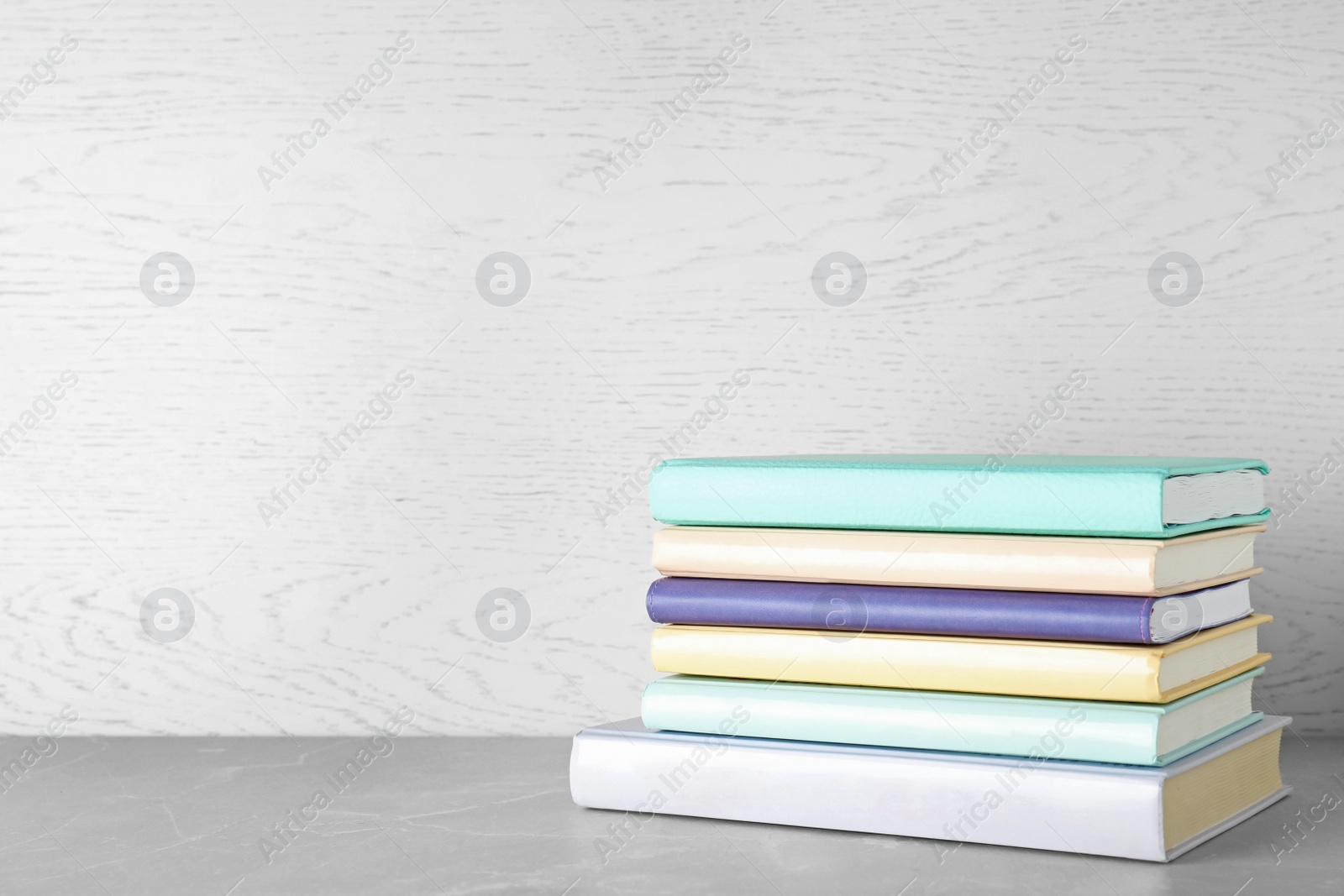 Photo of Stack of books on table against wooden background. Space for text