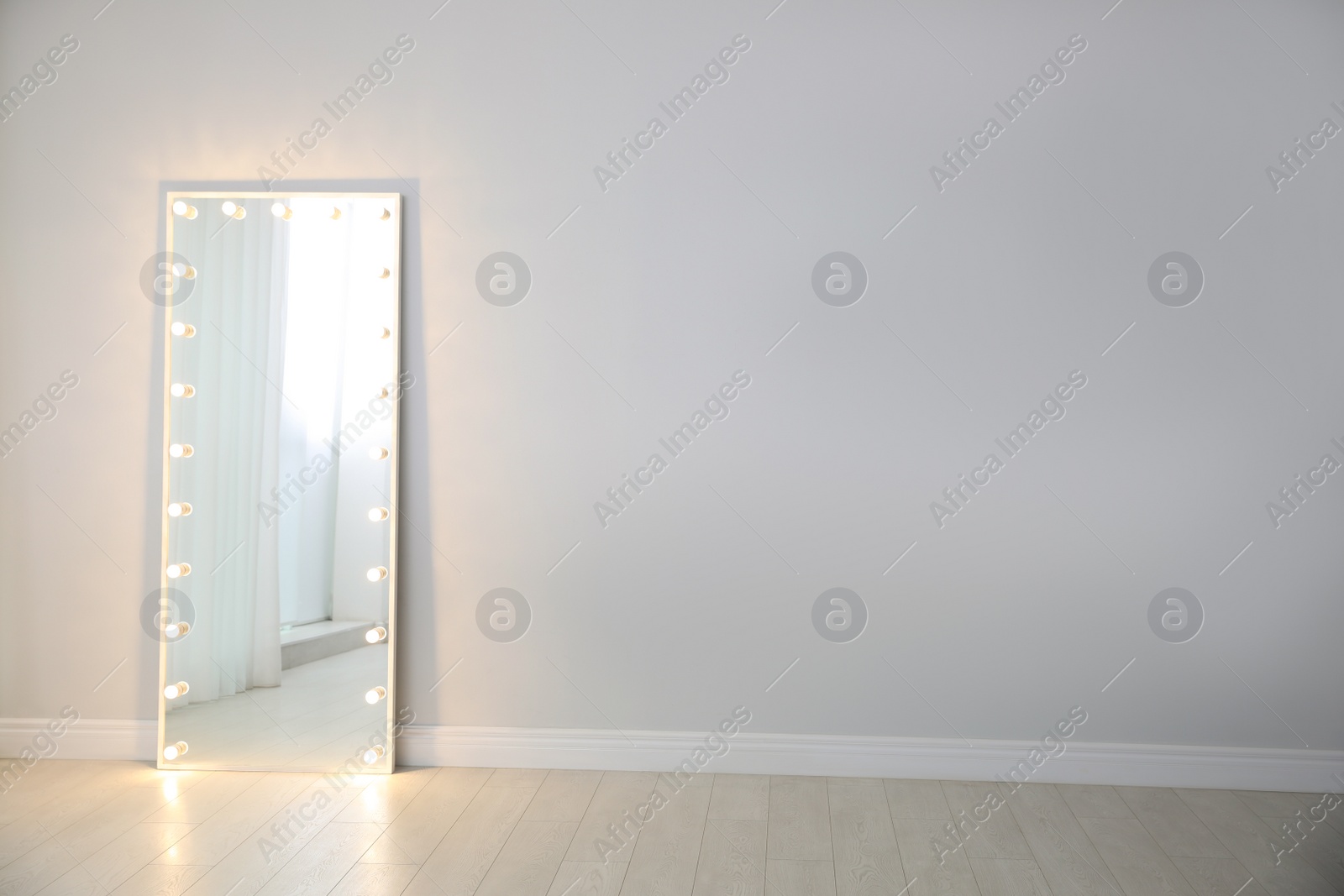 Photo of Large mirror with light bulbs near light wall indoors. Interior element