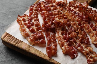 Photo of Slices of tasty fried bacon on black table