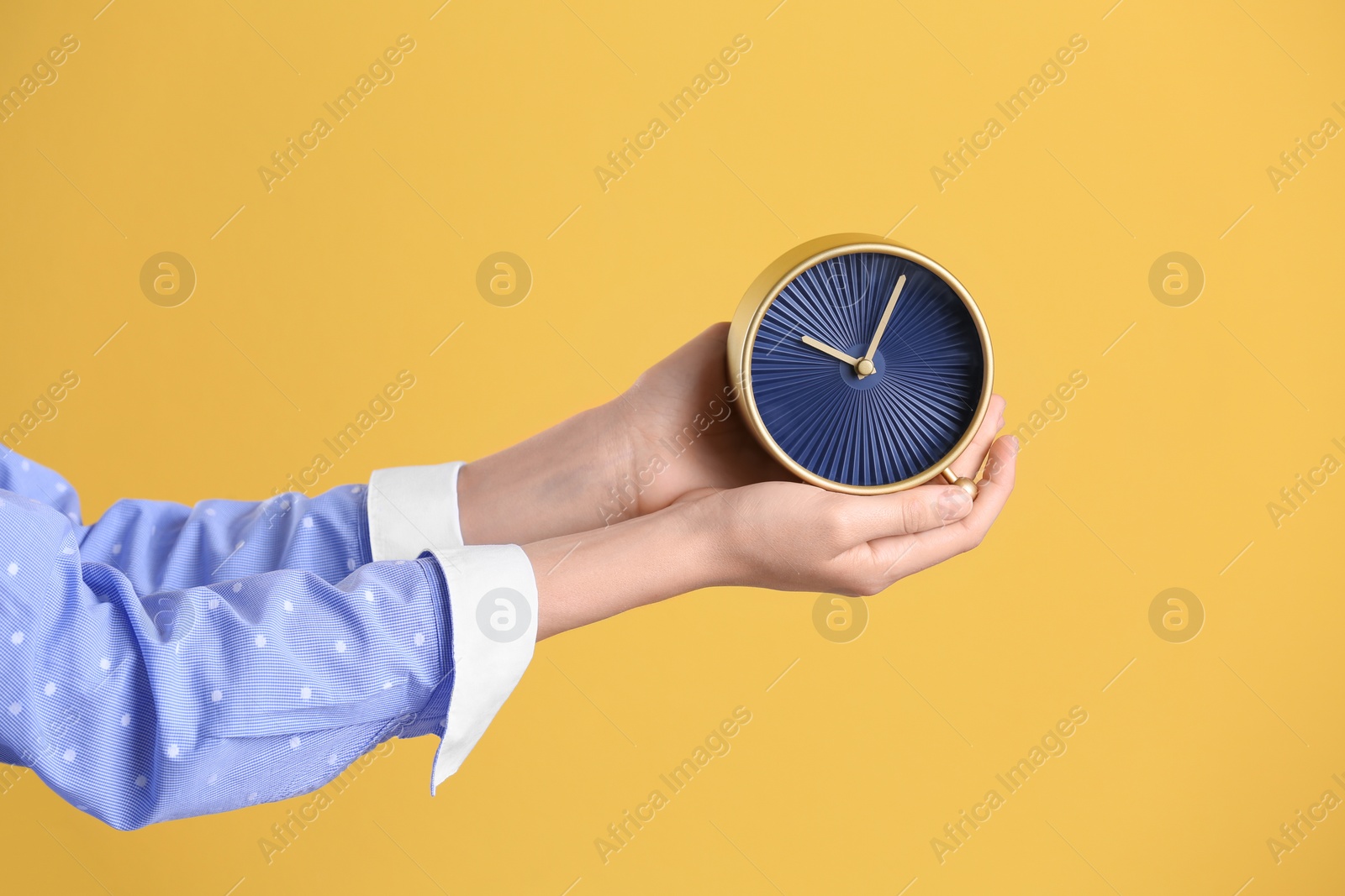 Photo of Young woman holding alarm clock on color background. Time concept