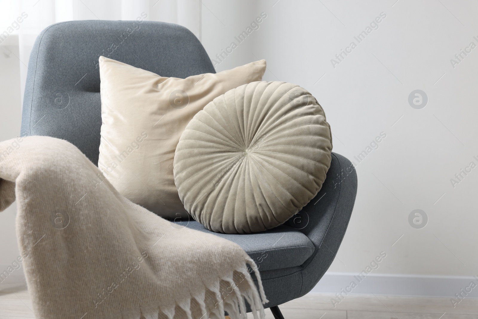 Photo of Soft pillows and blanket on armchair indoors