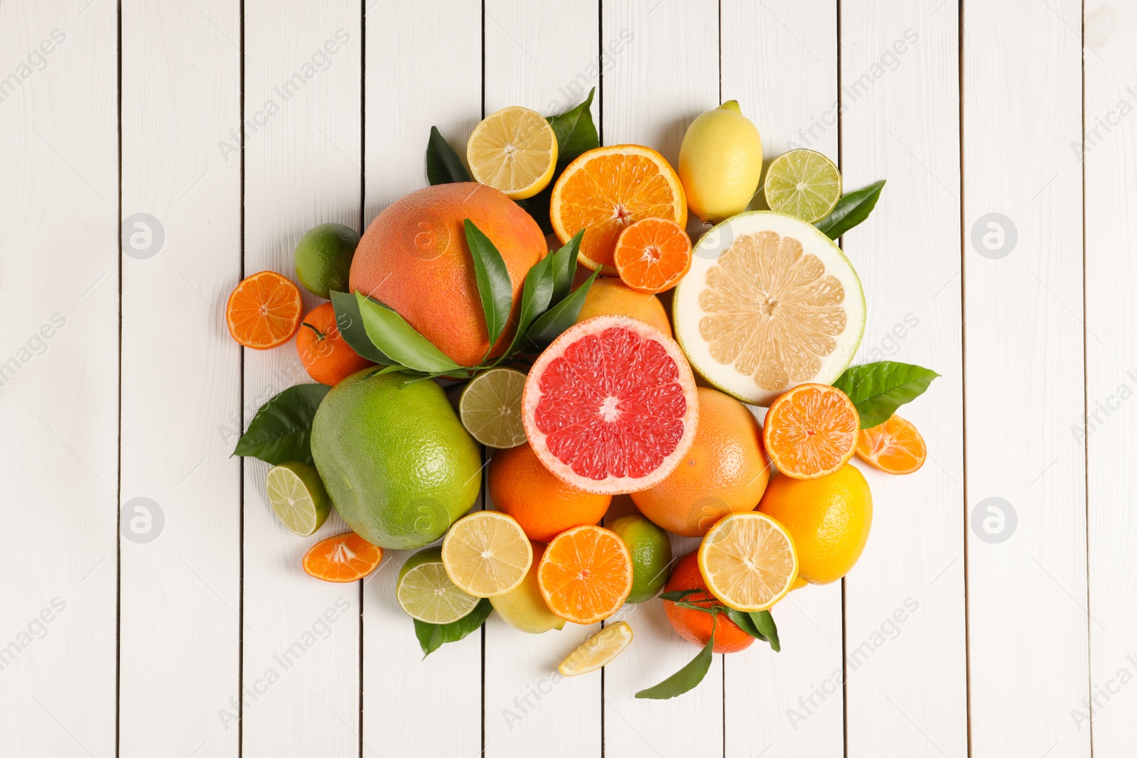 Photo of Different citrus fruits with fresh leaves on white wooden table, flat lay