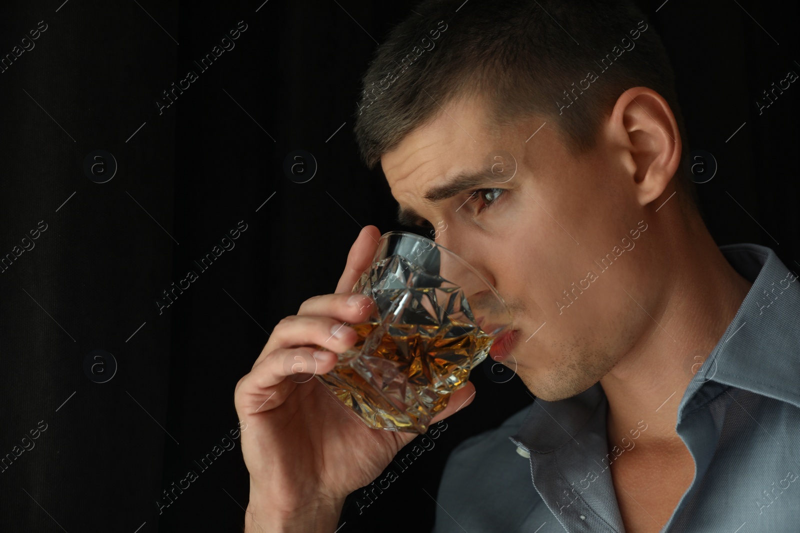 Photo of Young man with glass of whiskey indoors