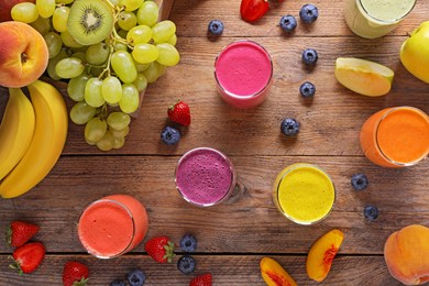 Photo of Many different tasty smoothies and ingredients on brown wooden table, flat lay