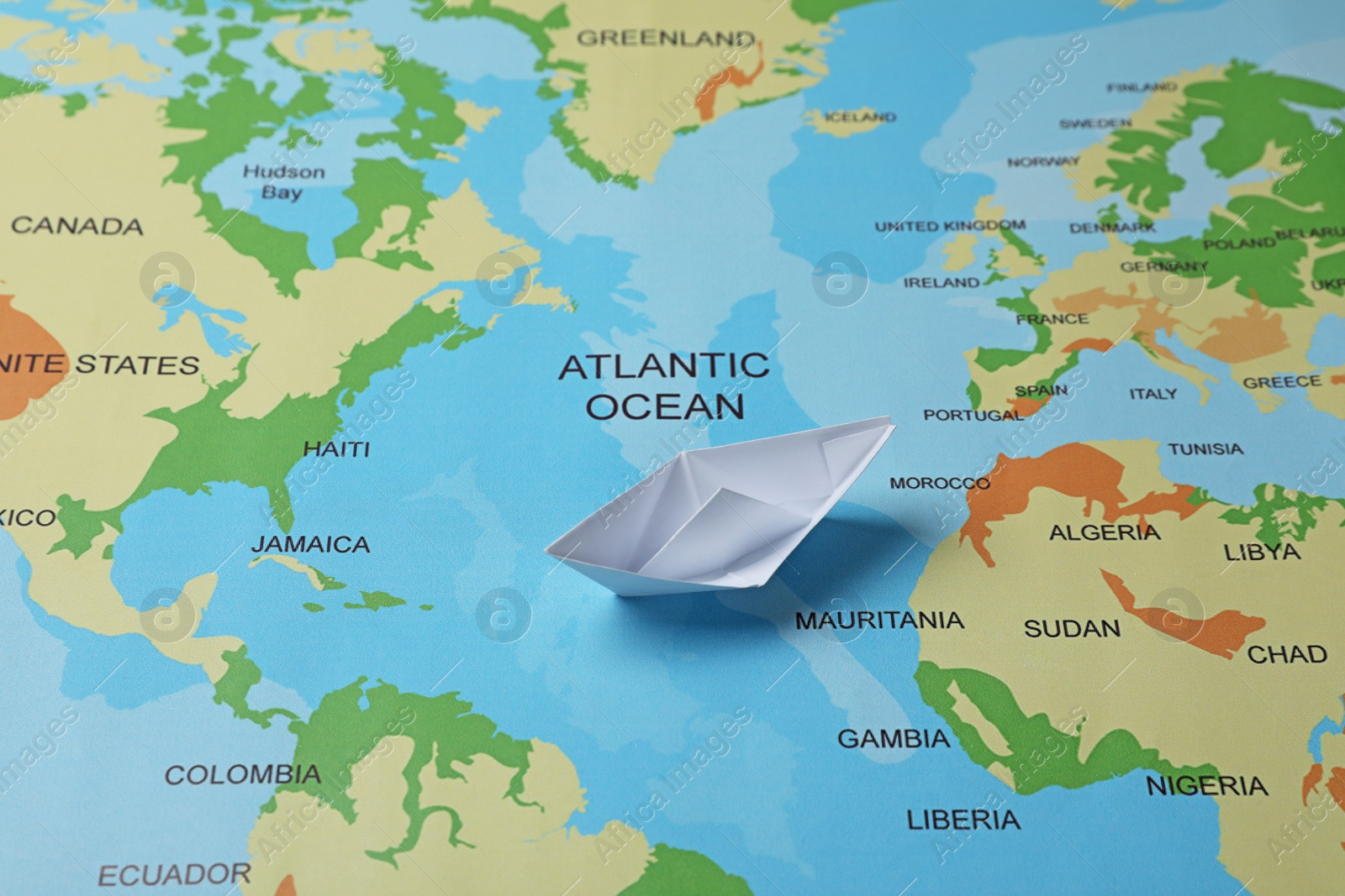 Photo of One white paper boat on world map