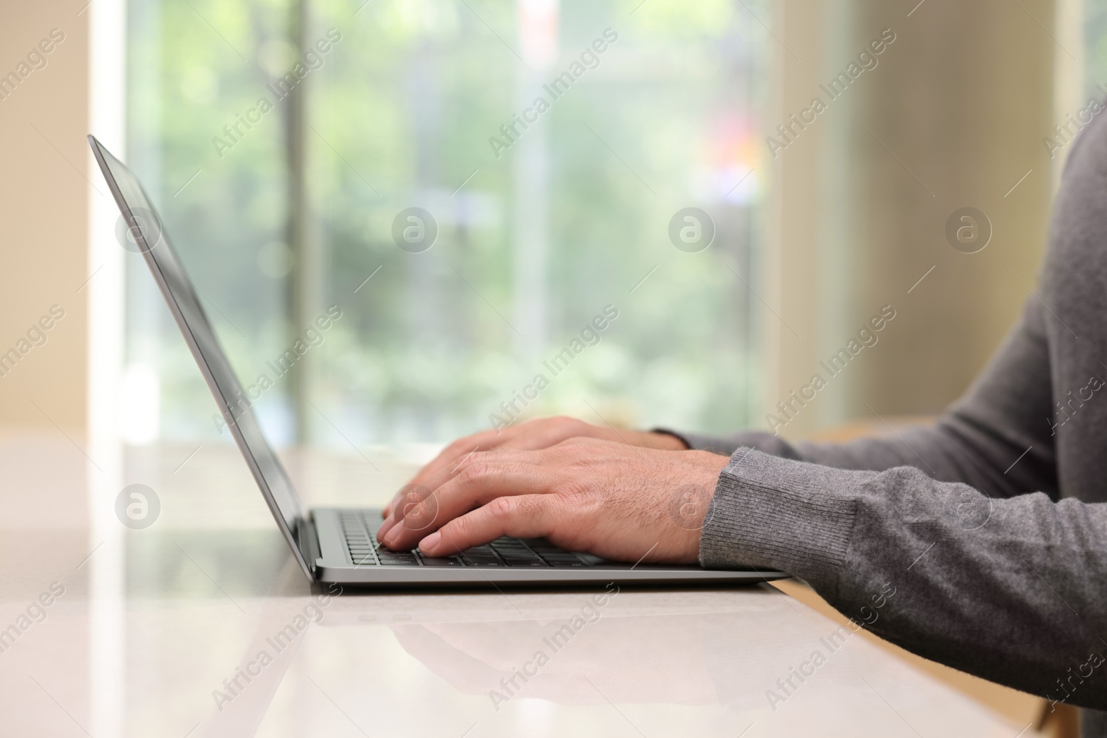 Photo of Man working on laptop at table in cafe, closeup