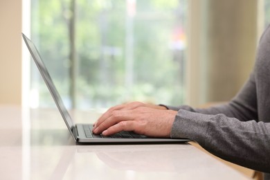 Man working on laptop at table in cafe, closeup