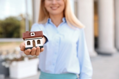 Female real estate agent with house model outdoors