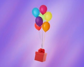 Many balloons tied to red gift box on bright background