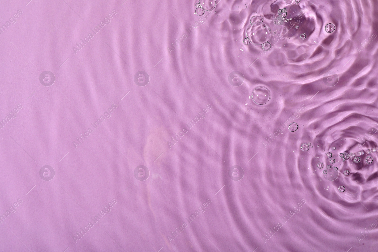 Photo of Closeup view of water with rippled surface on violet background