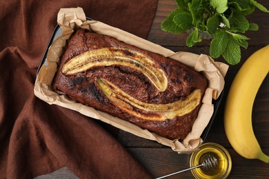 Photo of Delicious banana bread and ingredients on wooden table, flat lay