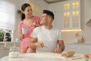 Happy couple wearing pyjamas and cooking together in kitchen