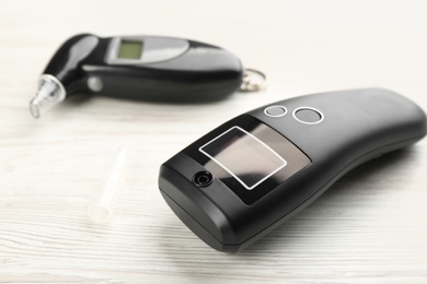 Photo of Modern breathalyzers lying on white wooden table