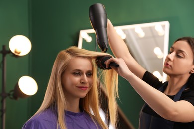 Stylist blow drying woman's hair in salon