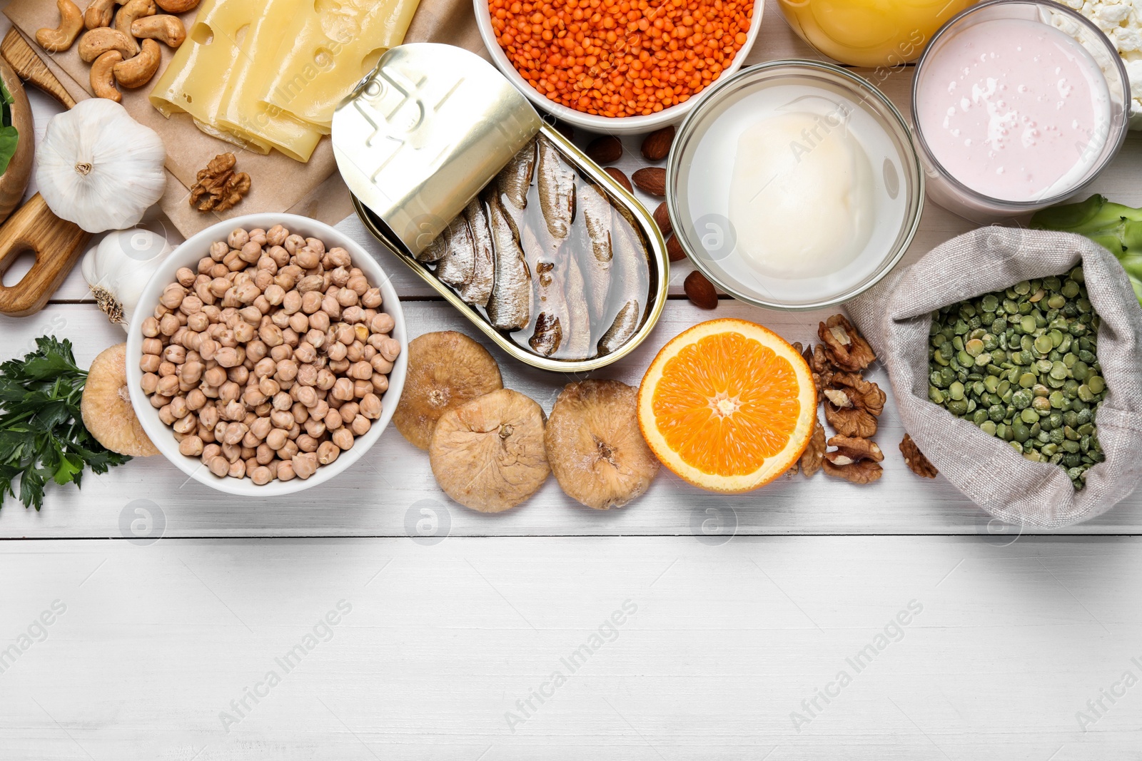 Photo of Set of natural food high in calcium on white wooden table, flat lay. Space for text