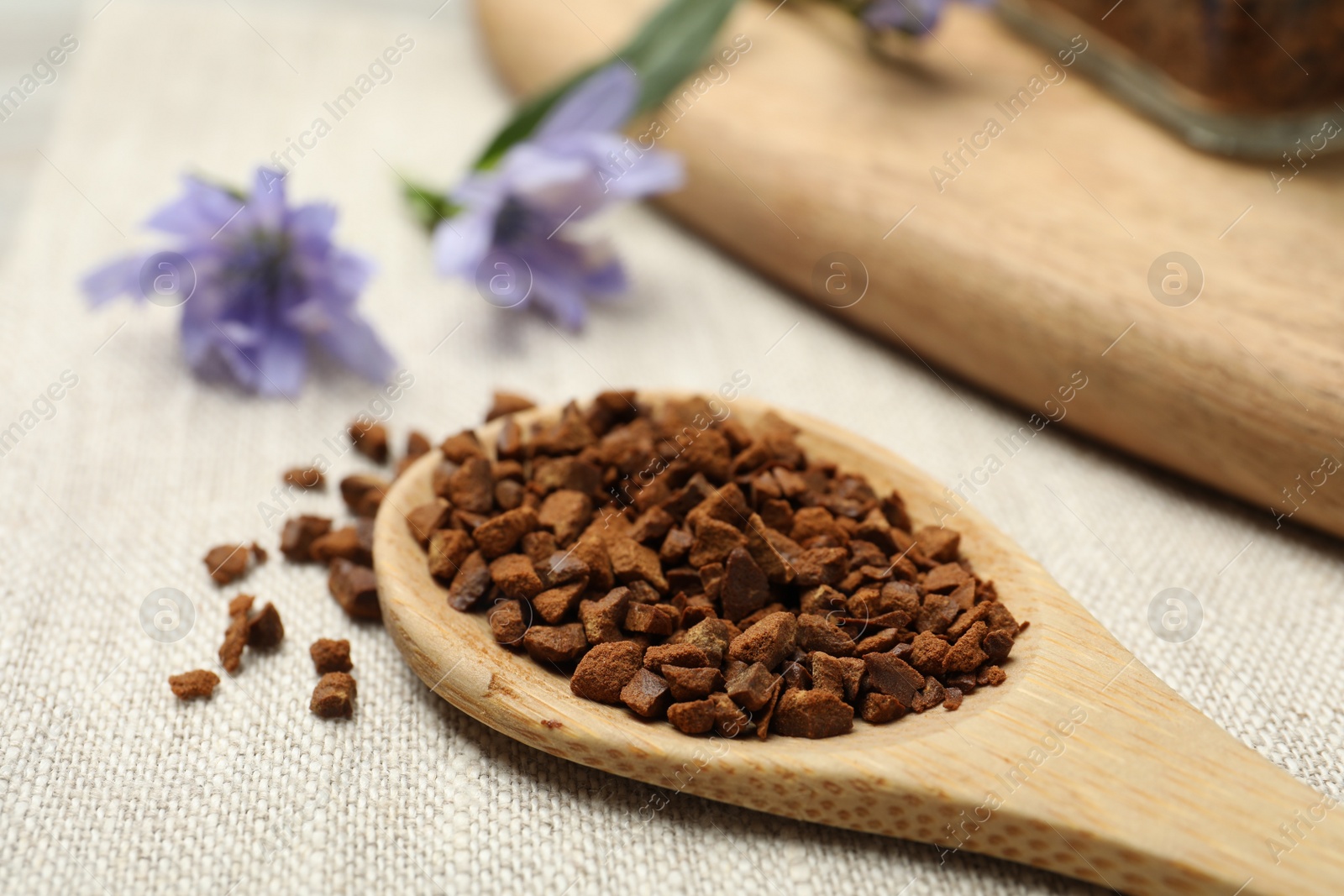 Photo of Wooden spoon of chicory granules on sackcloth, closeup