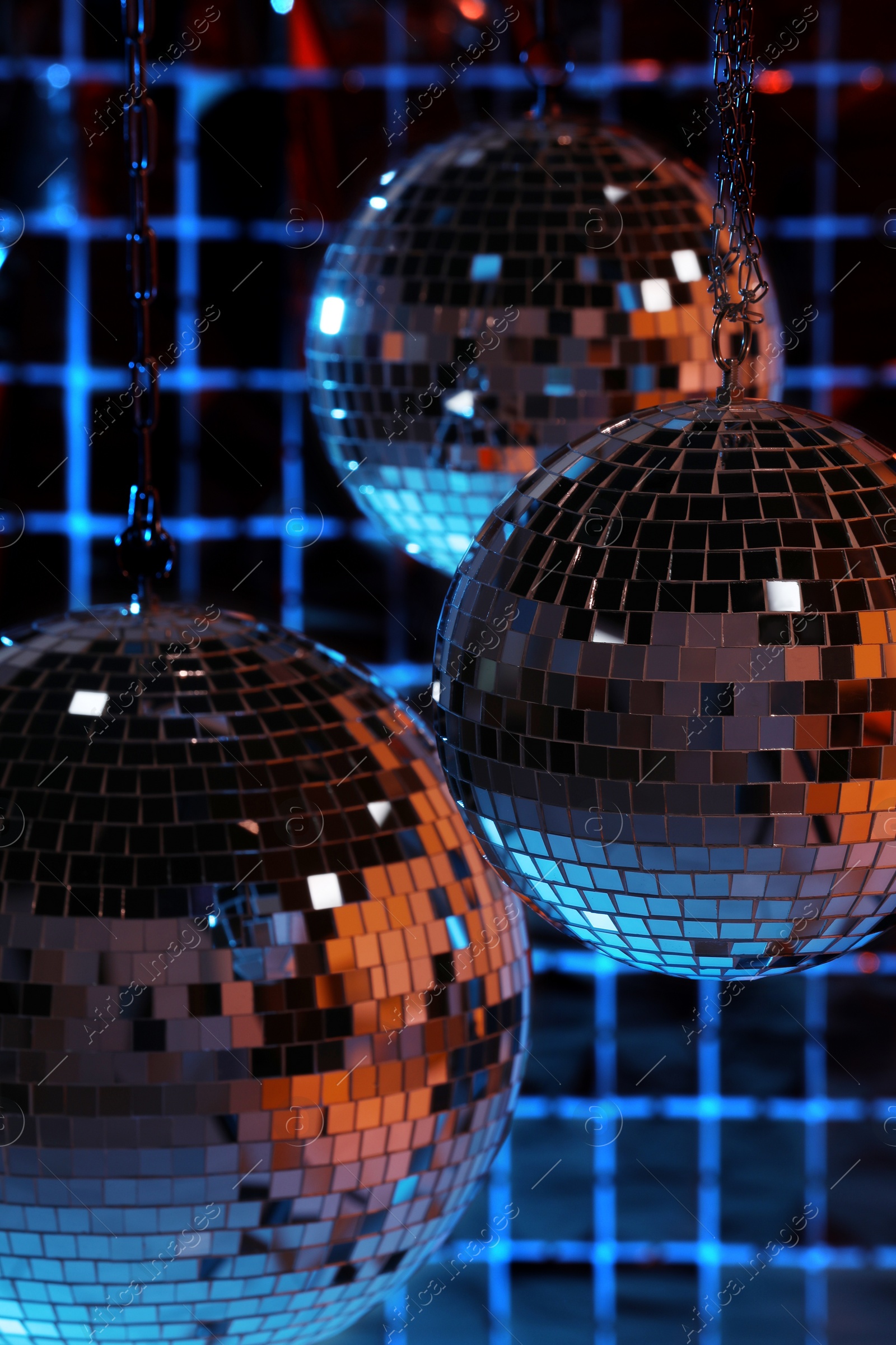 Photo of Shiny disco balls against foil party curtain under color lights