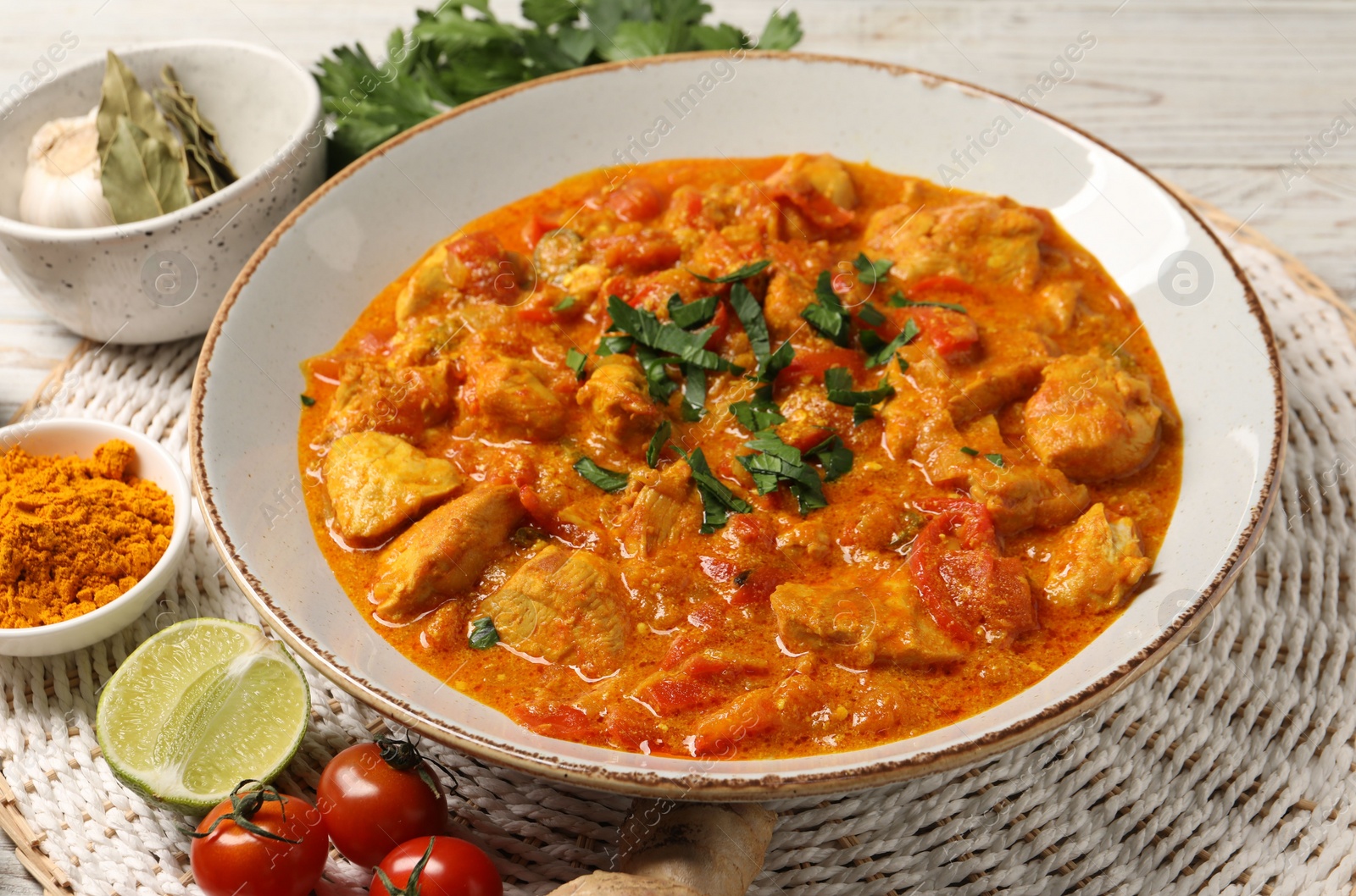 Photo of Delicious chicken curry and ingredients on table, closeup