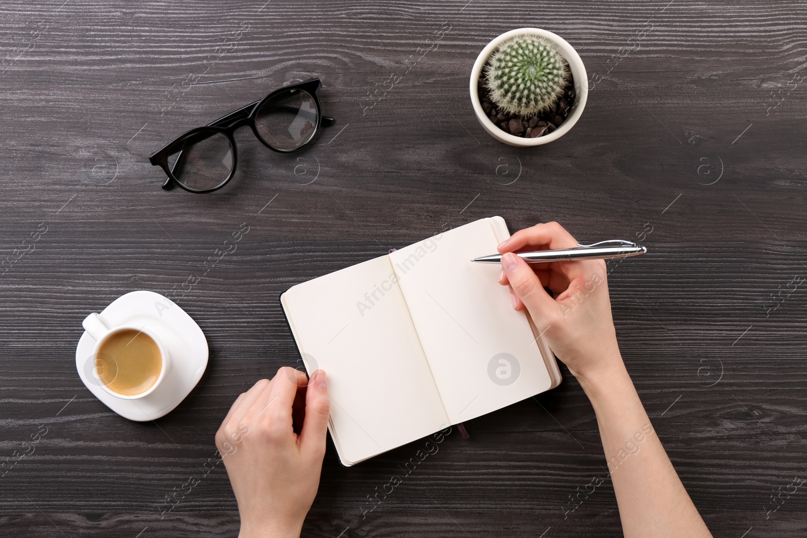 Photo of Woman with notebook and pen at grey wooden table, top view. Space for text