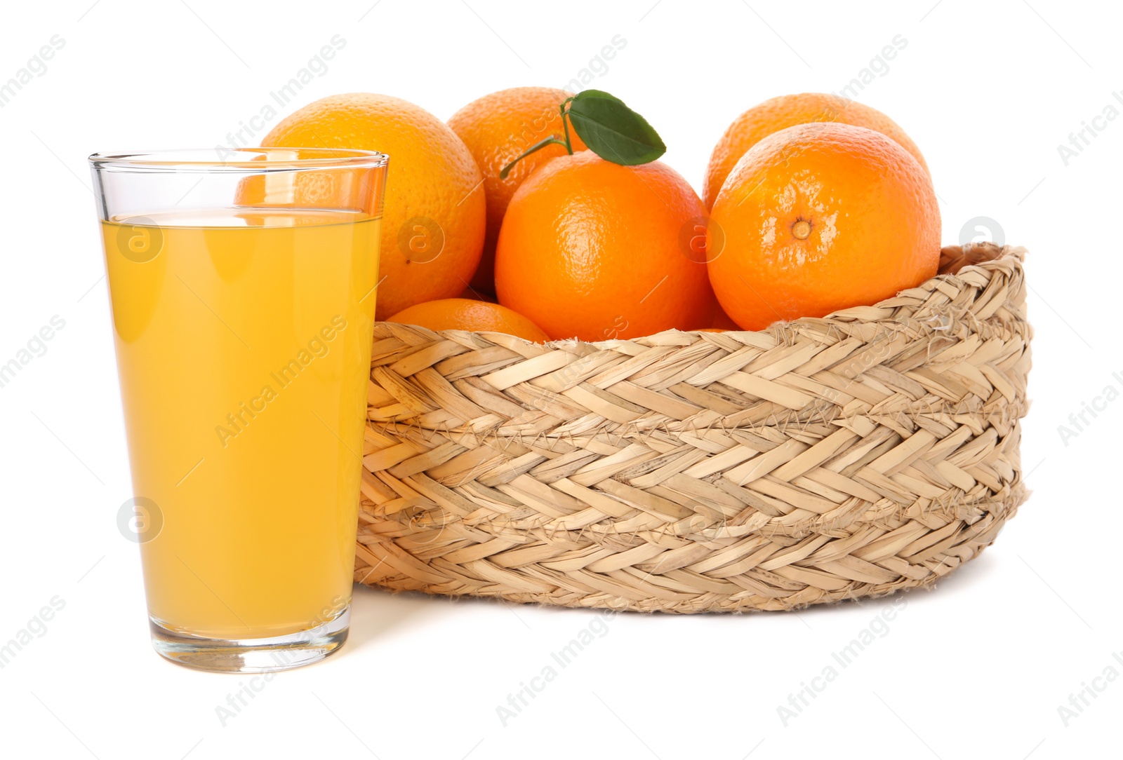 Photo of Fresh oranges in wicker basket and glass of juice isolated on white