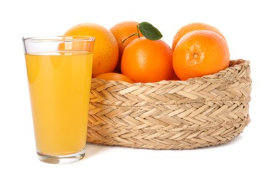 Fresh oranges in wicker basket and glass of juice isolated on white