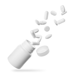 Image of Many different pills falling into bottle on white background