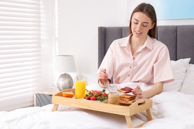 Photo of Smiling woman having breakfast in bed at home. Space for text