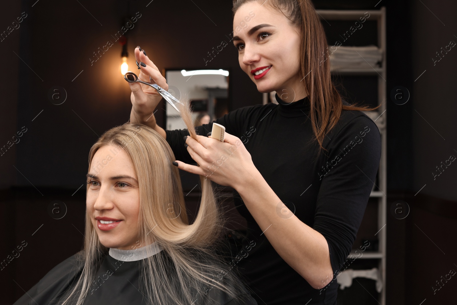 Photo of Professional hairdresser cutting woman's hair in salon