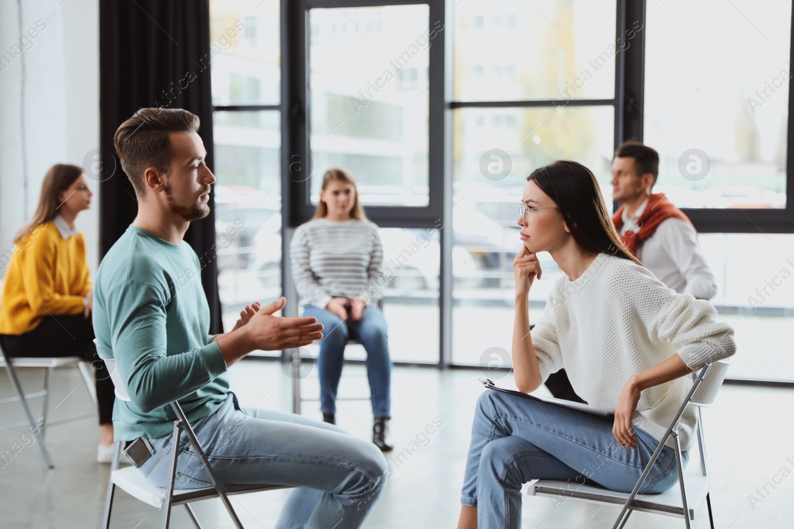 Photo of Psychotherapist working with patient in group therapy session indoors