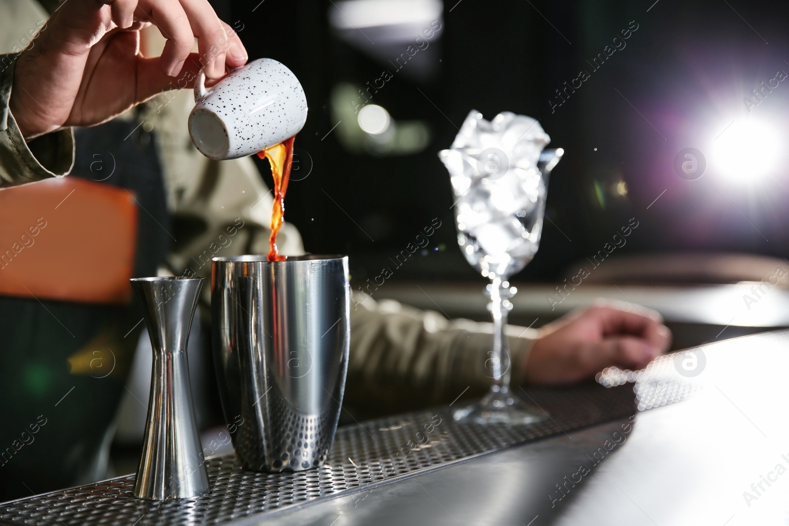 Photo of Barman pouring espresso into shaker at counter, closeup with space for text. Making martini cocktail