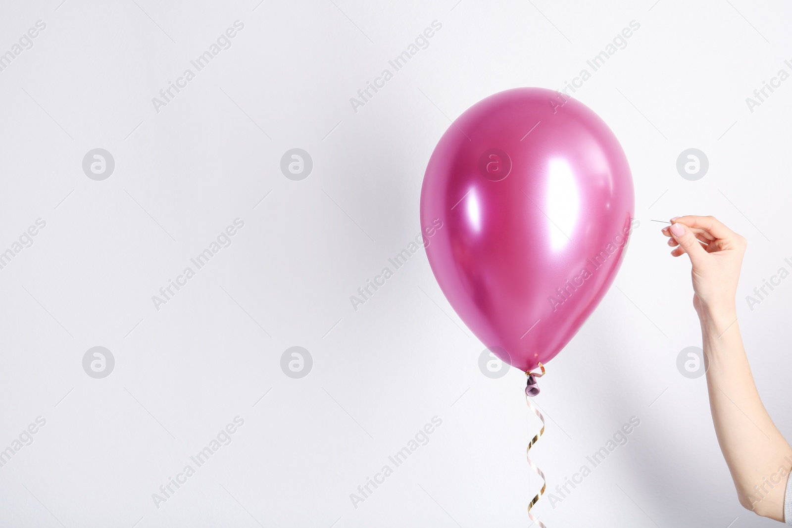 Photo of Woman piercing balloon with needle on white background, closeup