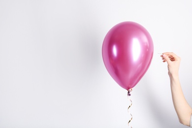 Woman piercing balloon with needle on white background, closeup