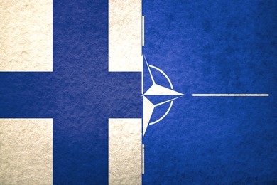 Flags of Finland and NATO on textured surface