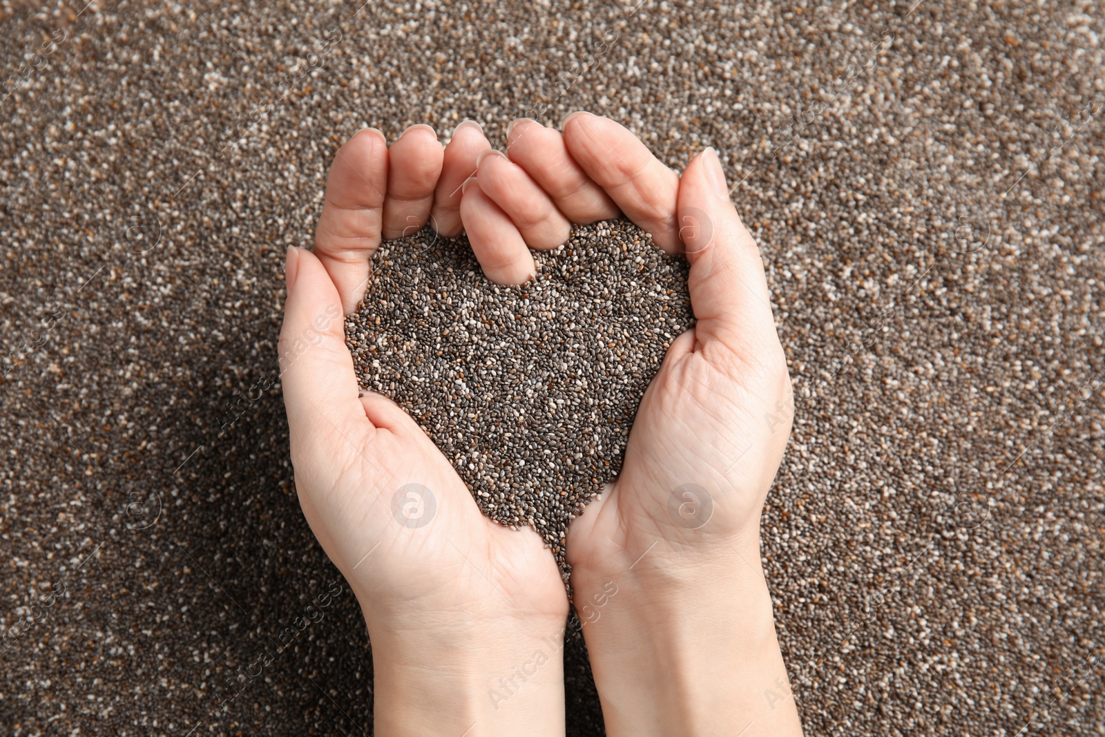 Photo of Woman holding heap of chia seeds, top view