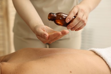 Photo of Aromatherapy. Woman receiving back massage with oil in spa salon, closeup