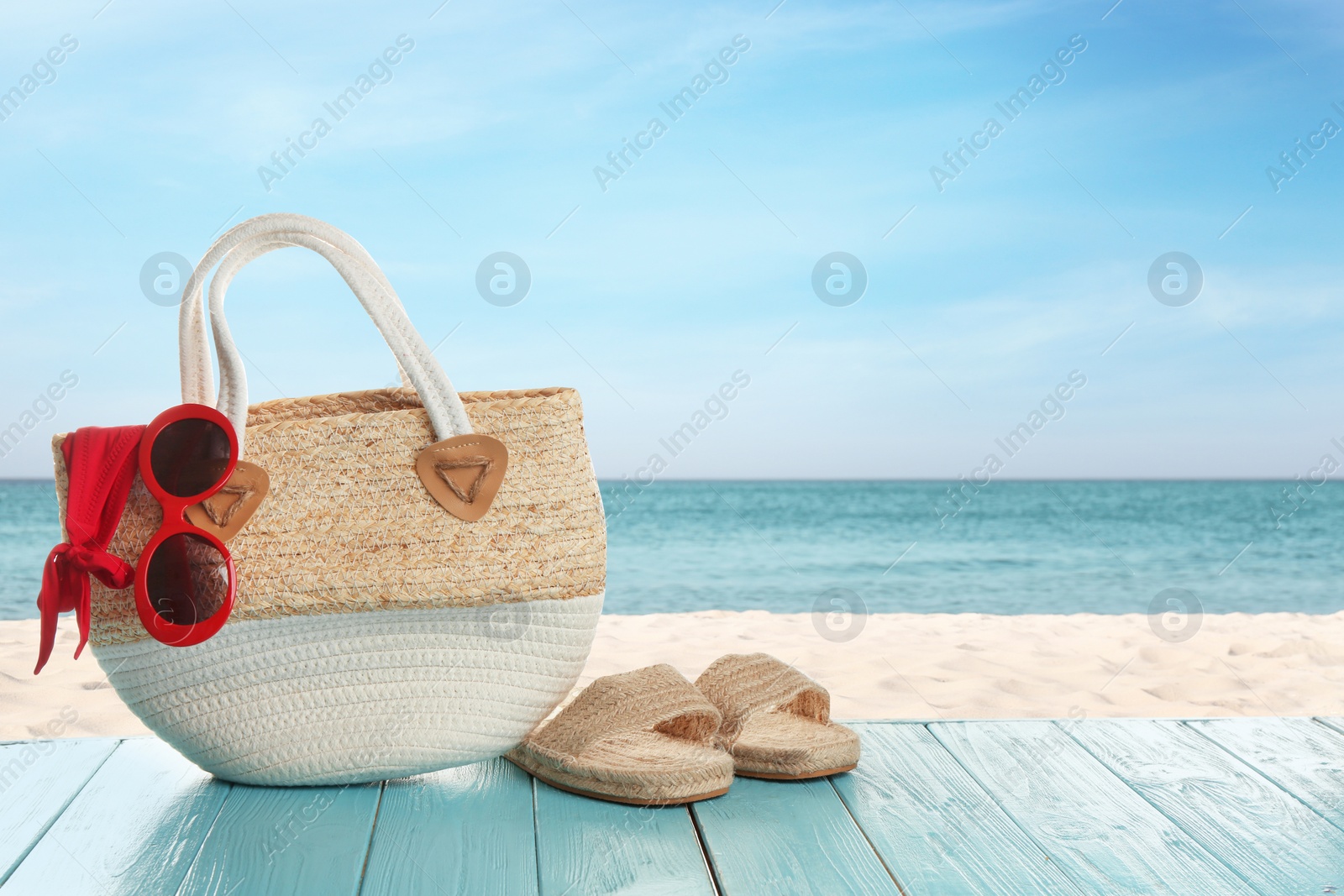 Image of Beach accessories on turquoise wooden surface near ocean, space for text