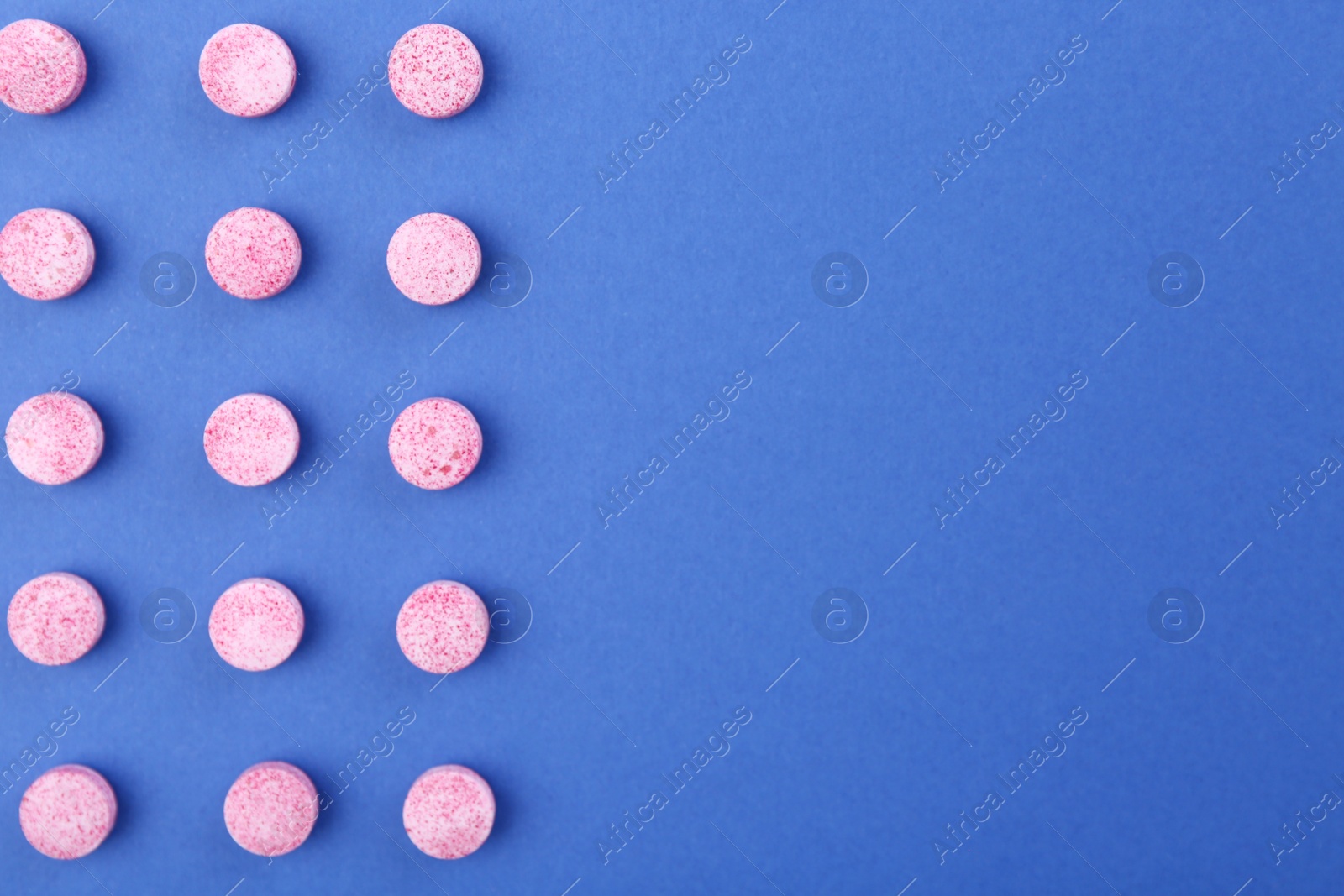 Photo of Many pink vitamin pills on blue background, flat lay. Space for text