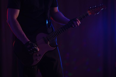 Photo of Man playing electric guitar on stage, closeup. Rock music