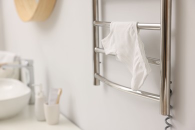 Heated towel rail with underwear on white wall in bathroom, closeup