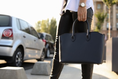 Photo of Young woman with stylish black bag on city street, closeup